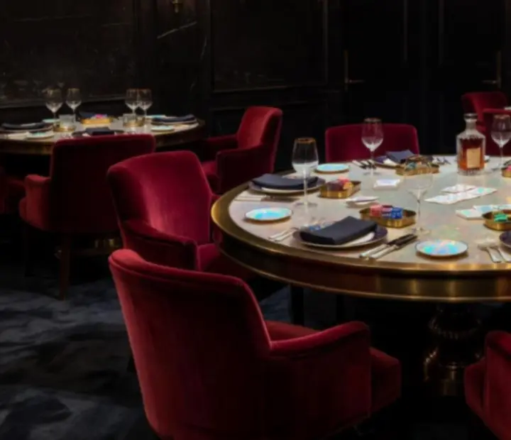Luxurious private poker table setup with fine dining place settings in a dark card lounge.